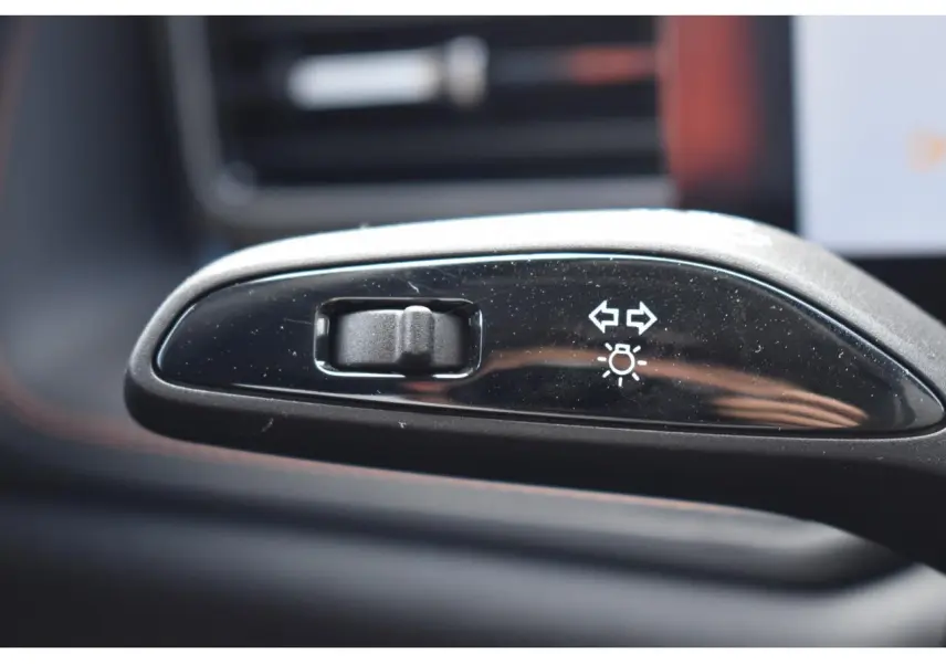 Gros plan sur le bouton de réglage des clignotants et feux, intérieur noir brillant du MG Motor EHS gris.