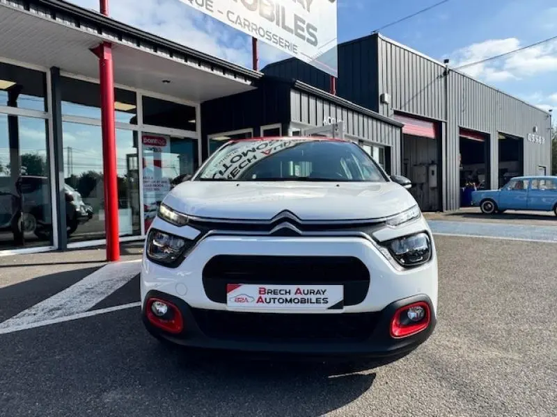 Vue avant frontale d'une Citroën C3 1.2 essence blanche avec toit rouge et entourages rouges sur pare-chocs.