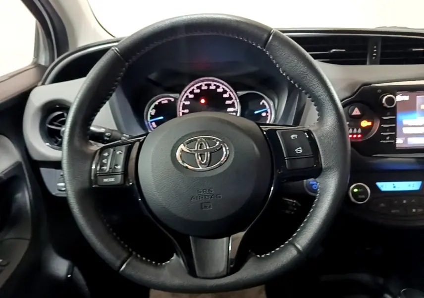 Vue intérieure centrée sur le volant cuir et alu multifonctions de la Toyota Yaris hybride 2019, tableau de bord visible.