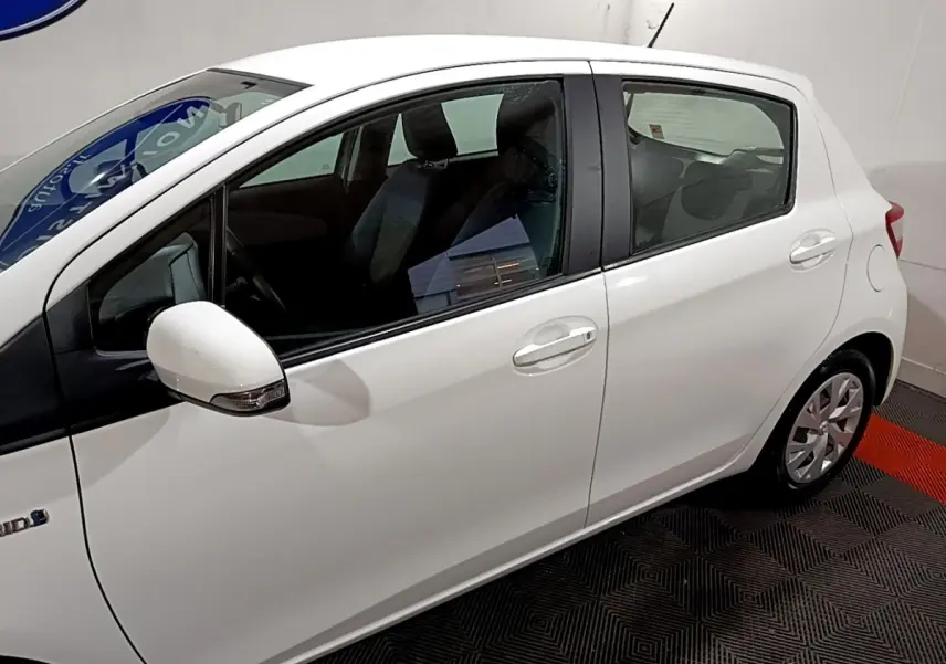 Vue latérale droite d'une Toyota Yaris blanche 2019 hybride avec rétroviseurs intégrant clignotants.