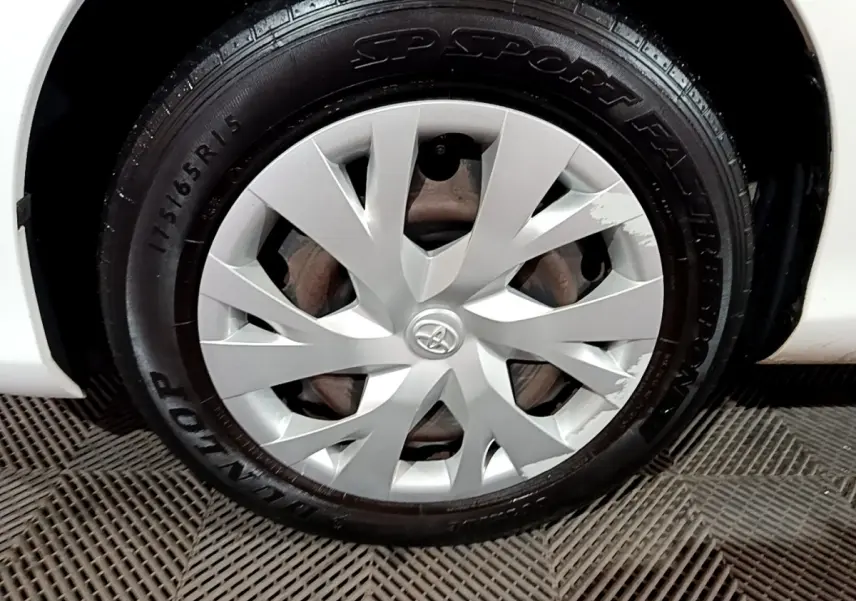Gros plan sur la roue avant gauche blanche d'une Toyota Yaris 1.5 VVT-I Hybrid avec enjoliveur argenté marqué Toyota.