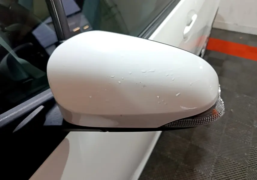 Rétroviseur droit blanc de la Toyota Yaris 1.5 VVT-I Hybrid France Business vu de près avec clignotant intégré.