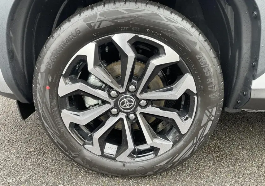 Gros plan sur la roue avant droite de la Toyota Yaris Cross gris clair avec jante alliage noire et argentée.