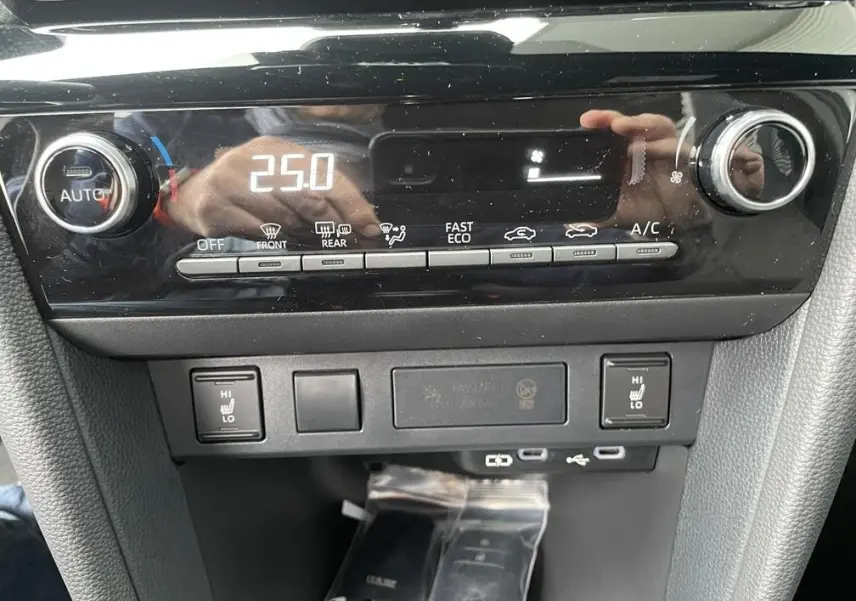 Gros plan sur la console centrale noire du Toyota Yaris Cross 2026, affichant la climatisation digitale et commandes chauffantes.