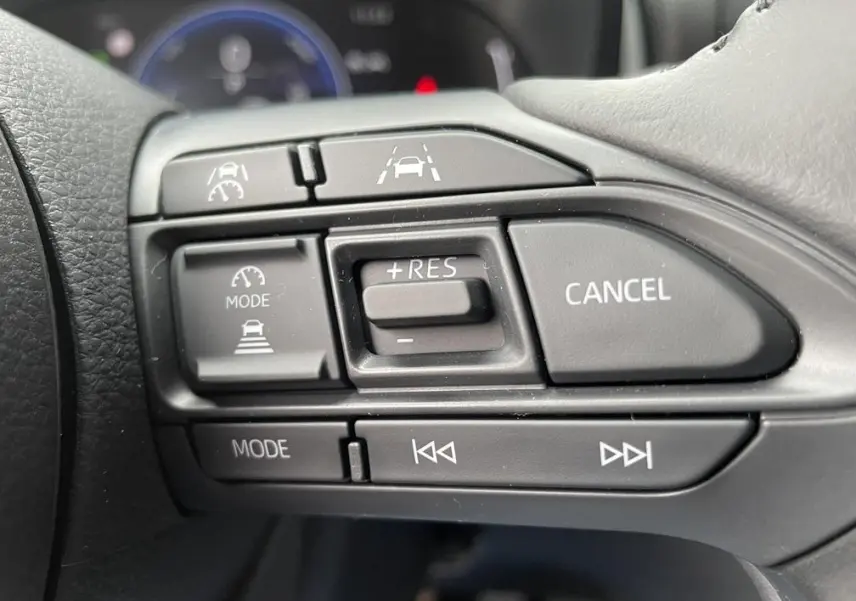 Gros plan sur les commandes du régulateur de vitesse au volant d’une Toyota Yaris Cross 2026 gris clair.