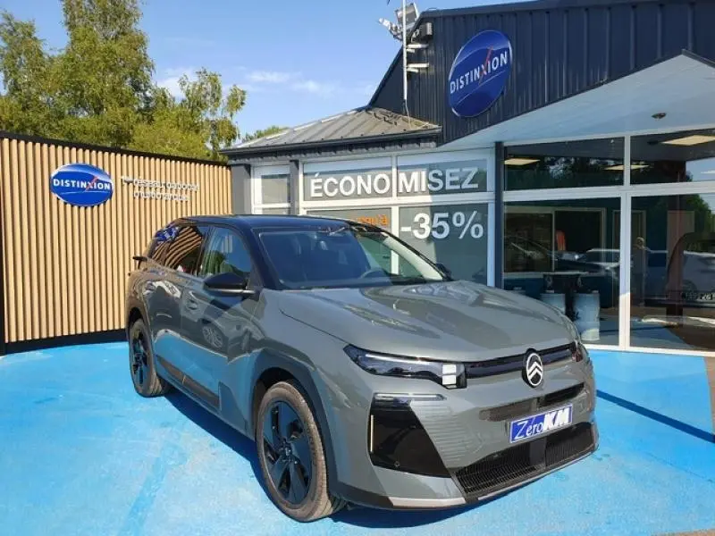 Vue 3/4 avant droite du Citroën C5 Aircross vert Astoria avec jantes noires devant un showroom Distinxion.