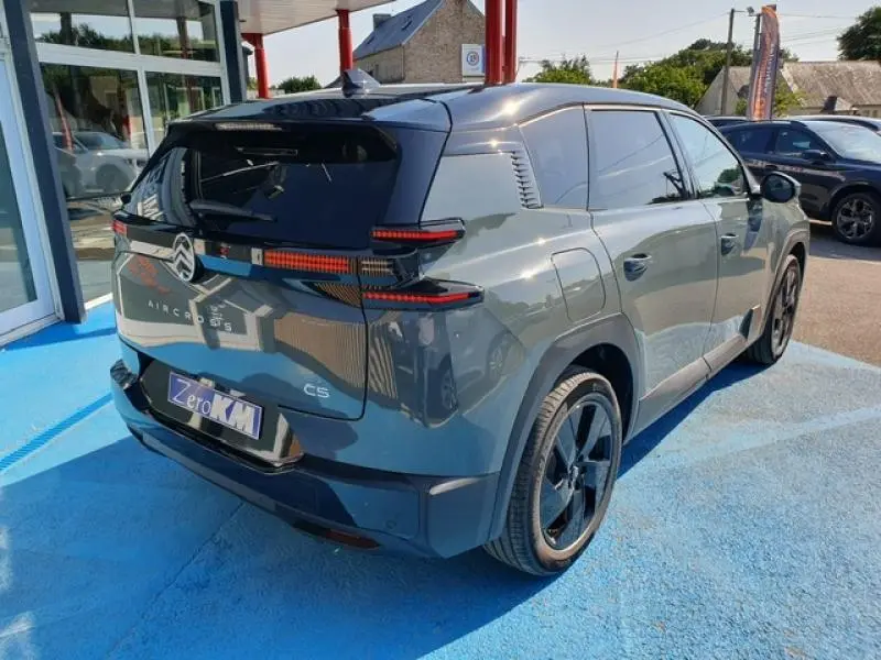 Vue 3/4 arrière droite d'un Citroën C5 Aircross vert Astoria avec vitres teintées et jantes noires.