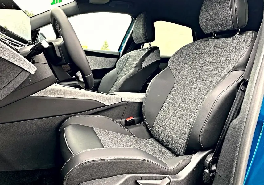 Vue intérieure côté conducteur du Peugeot 3008 bleu 2025, sièges tissu et cuir gris avec volant multifonction cuir.