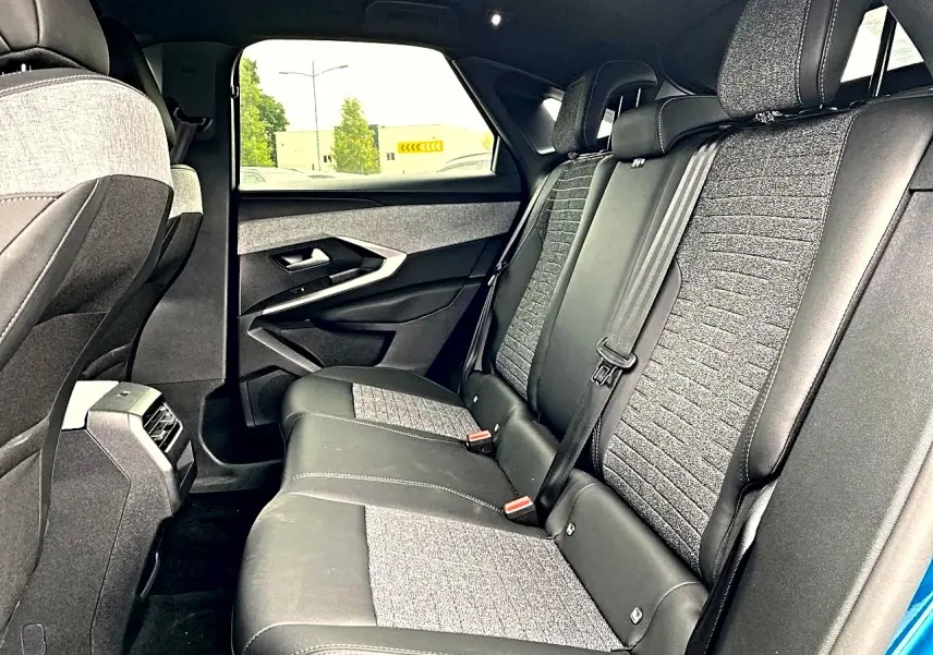 Vue intérieure arrière droite des sièges en tissu gris et cuir noir du Peugeot 3008 1.2 hybrid 145 allure bleu 2025.