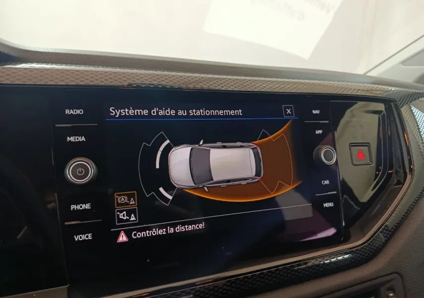 Écran tactile central du système d'aide au stationnement dans une Volkswagen Polo gris foncé, vue intérieure.