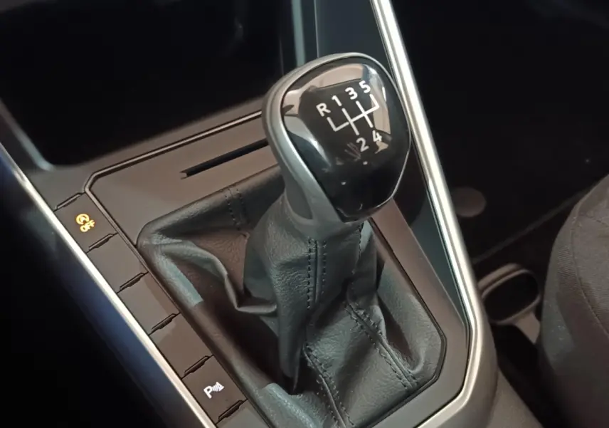 Gros plan sur le levier de vitesse manuel noir de la Volkswagen Polo 1.0 TSI 95 Life Plus, intérieur sombre.