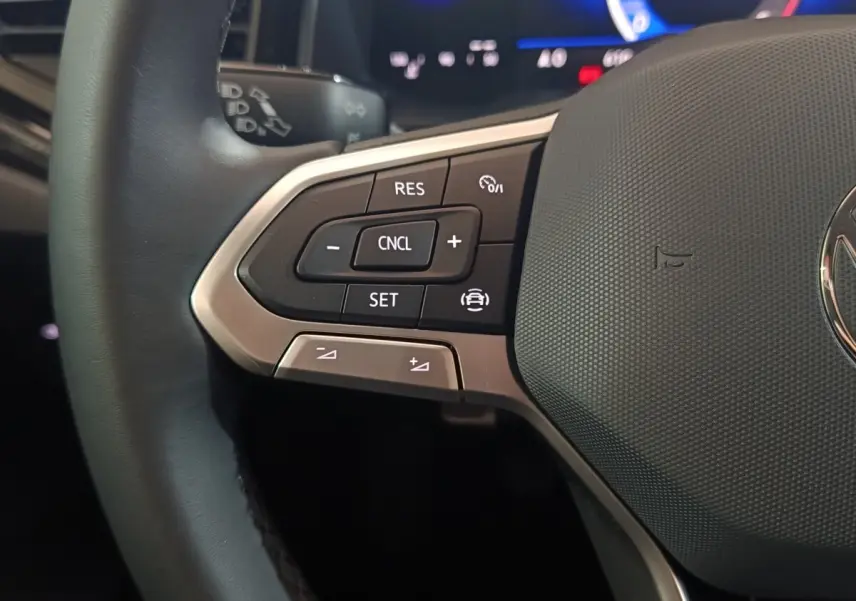 Gros plan sur la partie gauche du volant gris foncé de la Volkswagen Polo 2025 avec commandes multifonctions.
