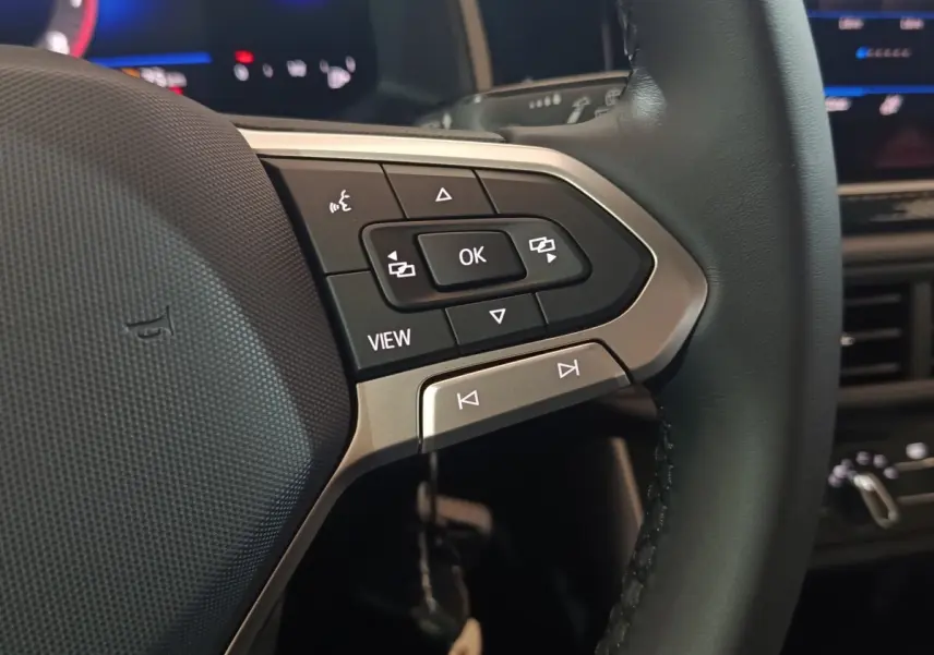Gros plan sur les commandes multifonctions à droite du volant cuir du Volkswagen Polo gris foncé, avec affichage numérique en arrière-plan.