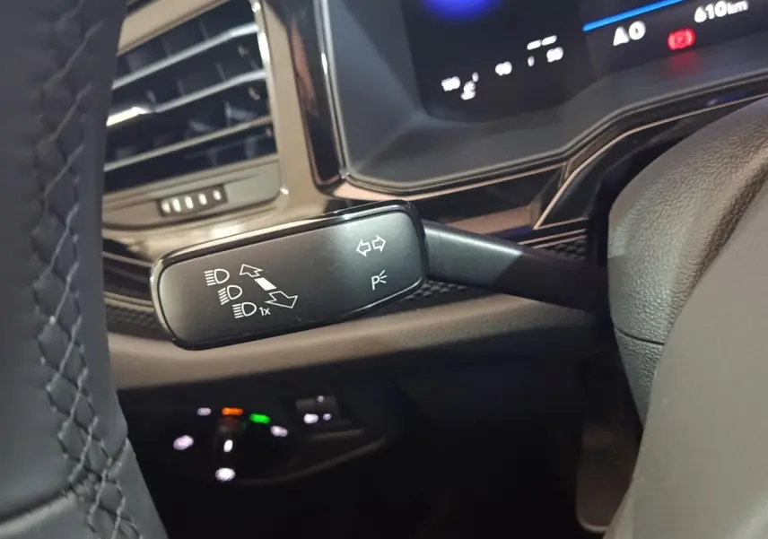 Gros plan sur le commodo gauche du volant d’une Volkswagen Polo gris foncé, avec tableau de bord numérique en arrière-plan.