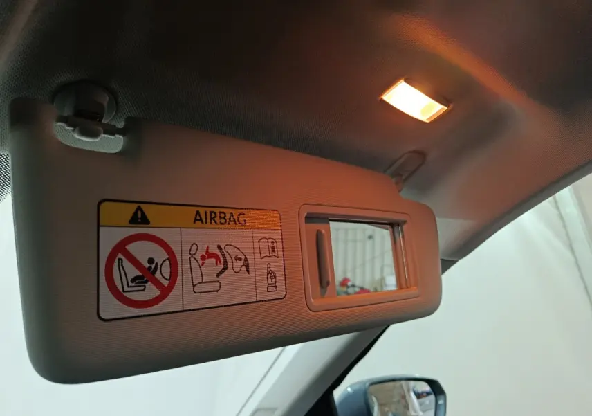 Vue intérieure du pare-soleil côté conducteur gris clair avec miroir et avertissement airbag éclairé.