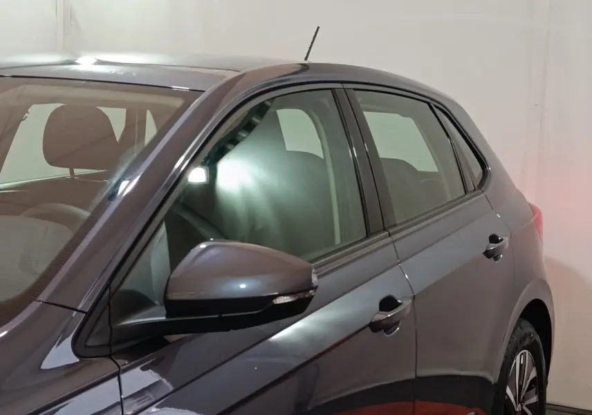 Vue côté gauche rapprochée d'une Volkswagen Polo gris foncé avec rétroviseur et poignées de porte visibles.