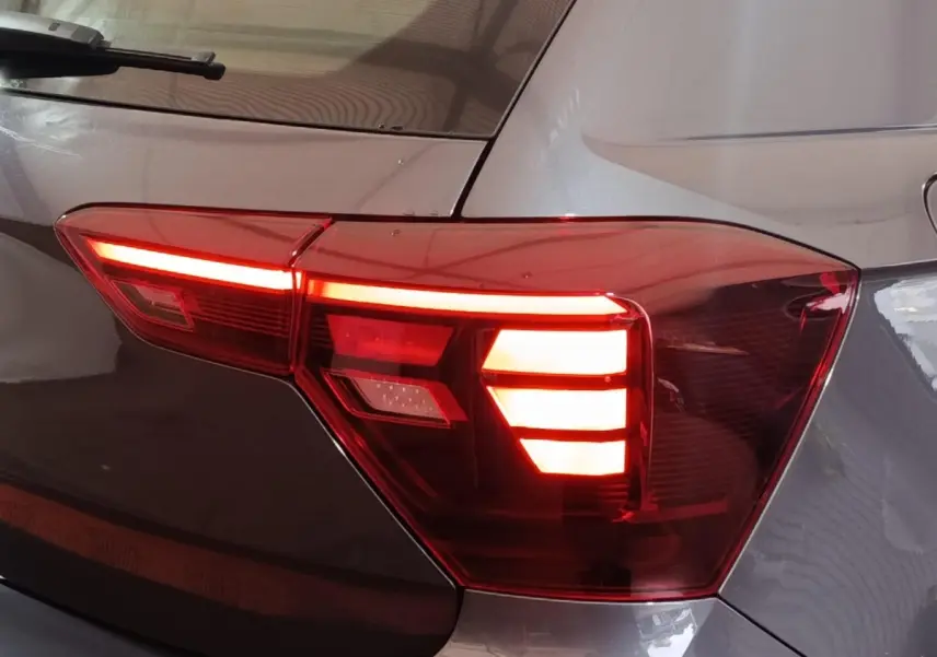 Gros plan sur le feu arrière droit allumé d'une Volkswagen Polo 2025 gris foncé, avec reflets sur la carrosserie.