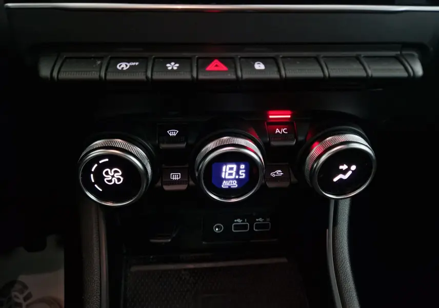 Gros plan sur la console de climatisation du Renault Captur 2024, avec réglage automatique à 18,5°C et boutons rétroéclairés.