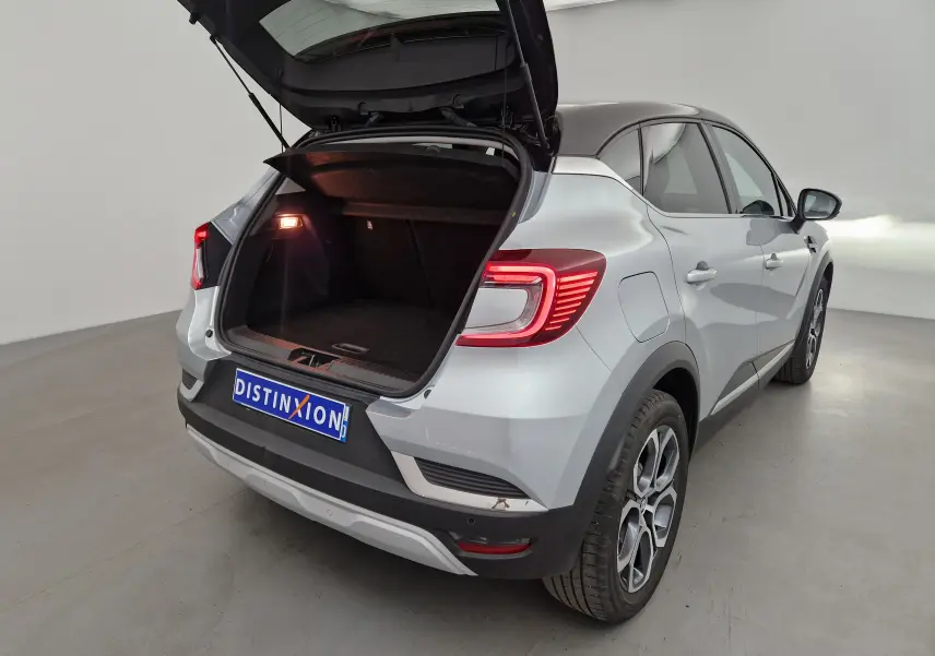 Renault Captur gris Highland/noir vue 3/4 arrière droit avec coffre ouvert et feux arrière allumés.