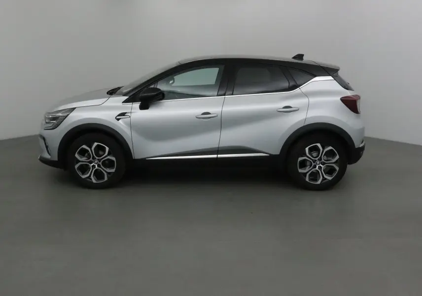 Profil côté gauche d'un Renault Captur 2024 gris Highland avec toit noir et jantes 18 pouces en alliage.