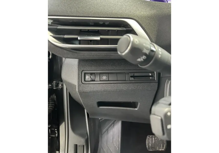 Détail des commandes sous le volant côté gauche du Peugeot 5008 noir métallisé 2024, avec bouton d'éclairage et aide à la conduite.