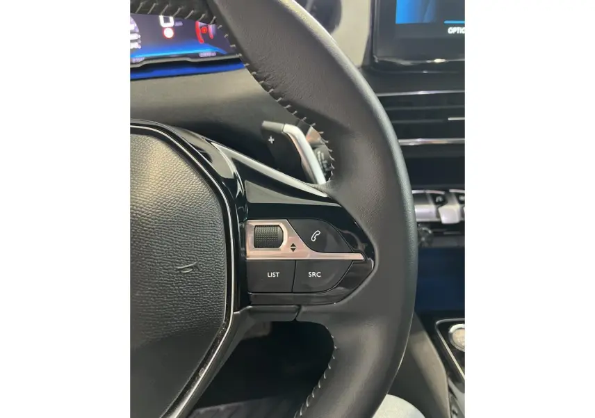 Gros plan sur le volant noir du Peugeot 5008 2024 avec commandes intégrées et tableau de bord numérique partiel visible.