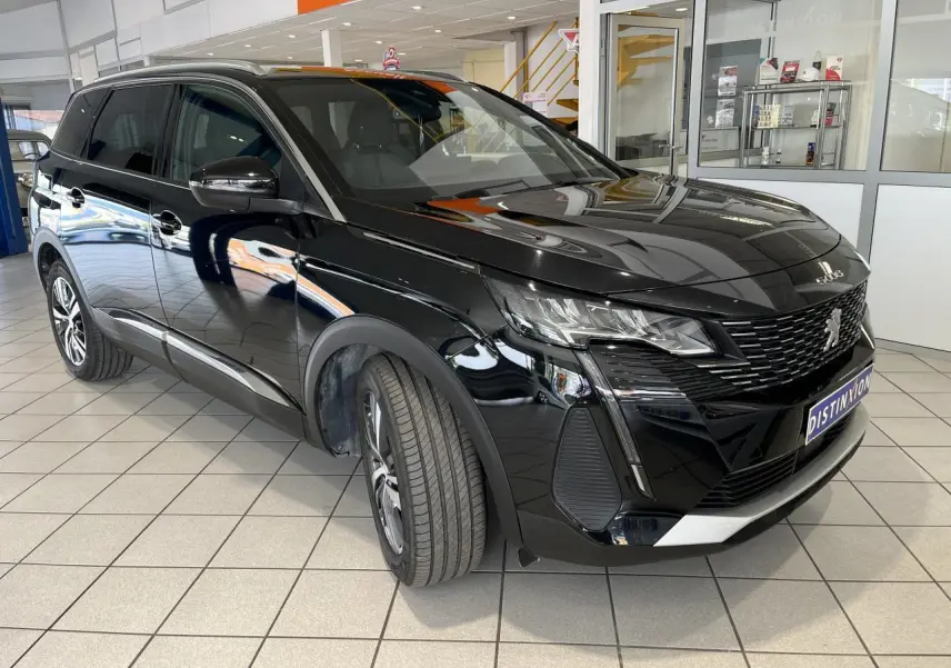 Peugeot 5008 noir métallisé en 3/4 avant droit, avec calandre à damier chromé et jantes alliage 18 pouces.