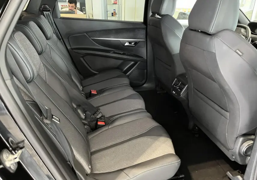 Vue intérieure côté gauche des sièges arrière en tissu et cuir du Peugeot 5008 noir métallisé 2024 avec finitions carbone.