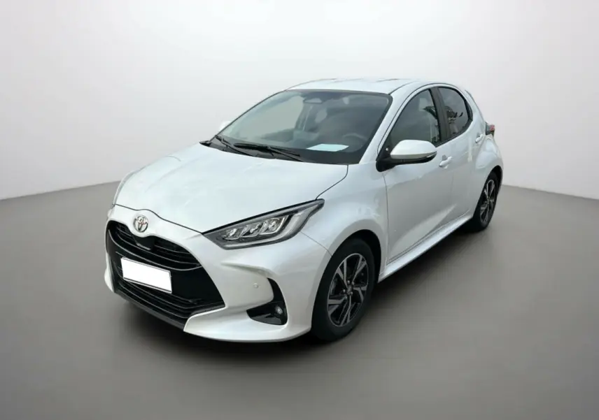 Toyota Yaris 2025 blanc lunaire vue 3/4 avant droit avec calandre noire et jantes alliage bicolores.