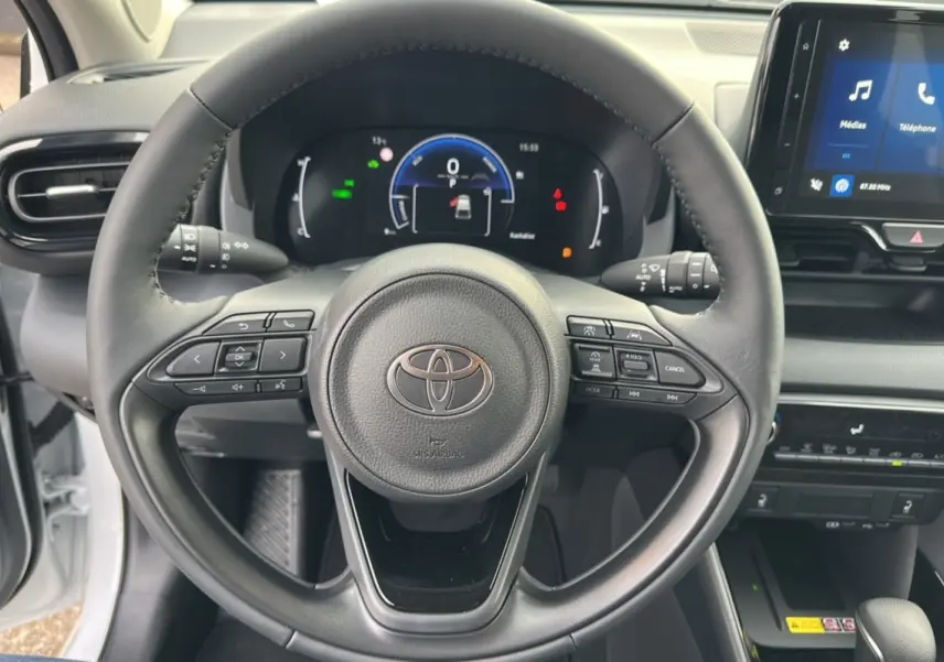 Vue rapprochée du volant et du tableau de bord numérique d'une Toyota Yaris blanche lunaire 2025 hybride.