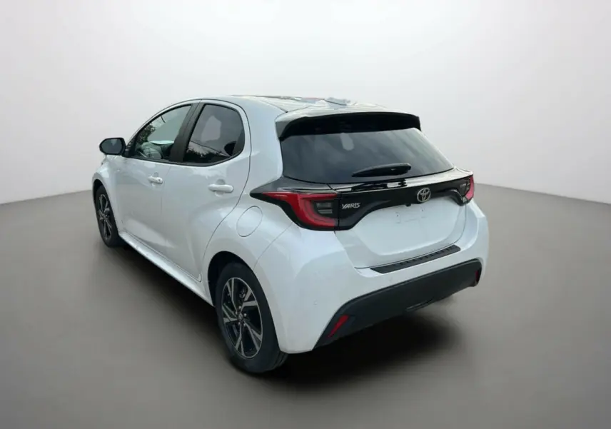 Toyota Yaris 2025 blanc lunaire vue 3/4 arrière côté gauche avec toit noir et feux arrière distinctifs.