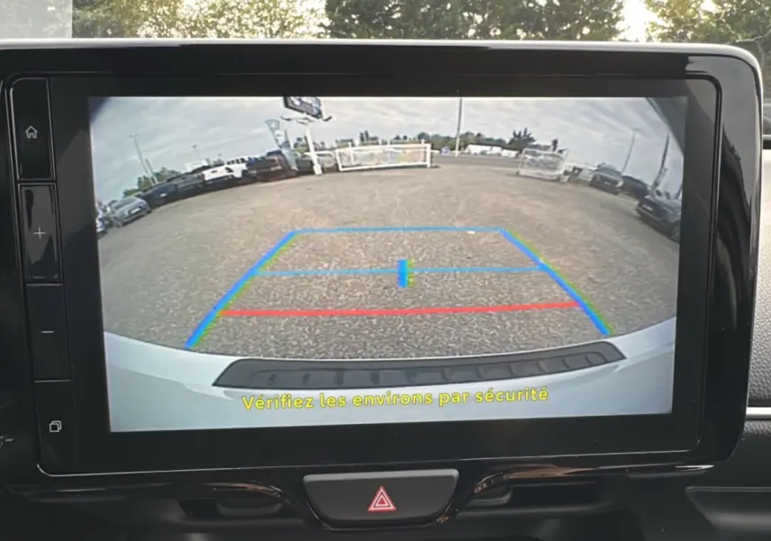 Vue caméra de recul arrière de la Toyota Yaris 2025 blanc lunaire avec lignes de guidage colorées sur écran tactile.