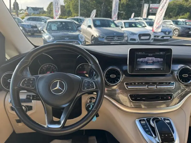 Vue intérieure du tableau de bord beige et volant cuir noir d'un Mercedes Classe V 250 d Long Avantgarde 2019.