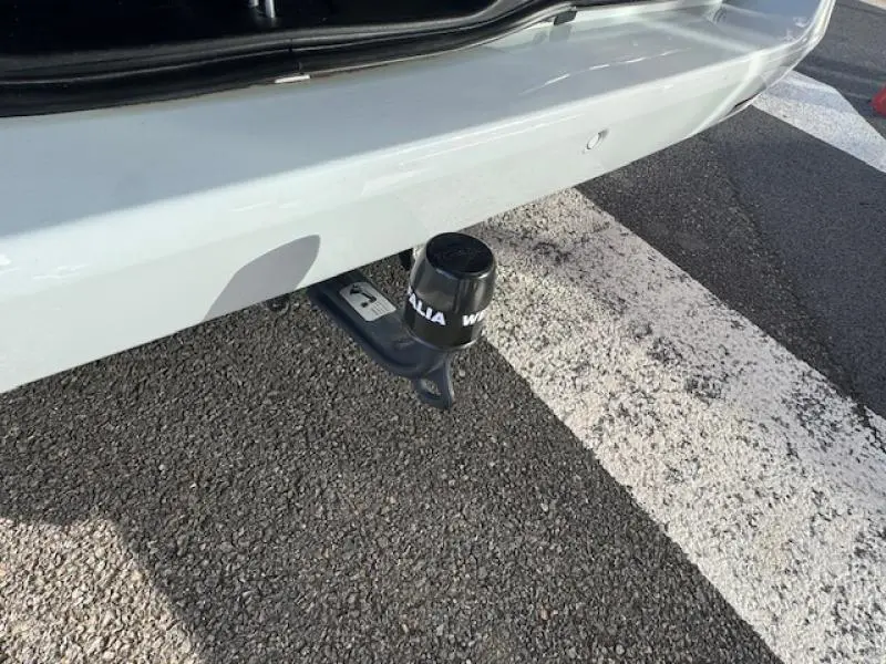 Gros plan sur l'attelage de remorquage noir sous le pare-chocs arrière blanc cristal de roche métallisé du Mercedes Classe V 250 d.