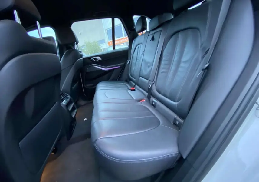 Vue intérieure arrière côté droit du BMW X5 blanc 2022, sièges en cuir noir avec finitions M Sport.