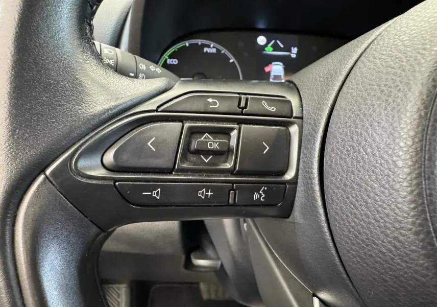 Gros plan sur les commandes multifonctions noires du volant côté gauche de la Toyota Yaris hybride 2022.