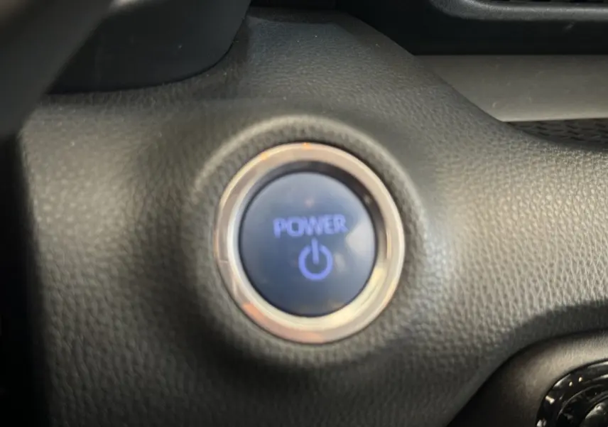 Gros plan sur le bouton de démarrage Power entouré de cuir noir dans l’habitacle de la Toyota Yaris hybride 2022.