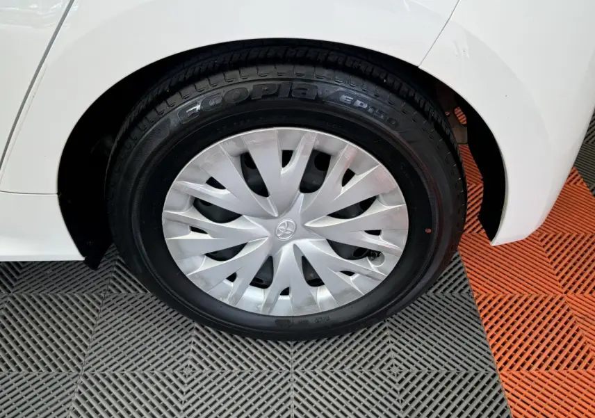 Gros plan sur la roue arrière droite blanche d'une Toyota Yaris hybride 2022 avec enjoliveur argenté et logo Toyota central.