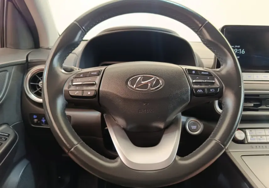 Vue rapprochée du volant cuir multifonctions d’une Hyundai Kona électrique 2023 avec tableau de bord et bouton start/stop.