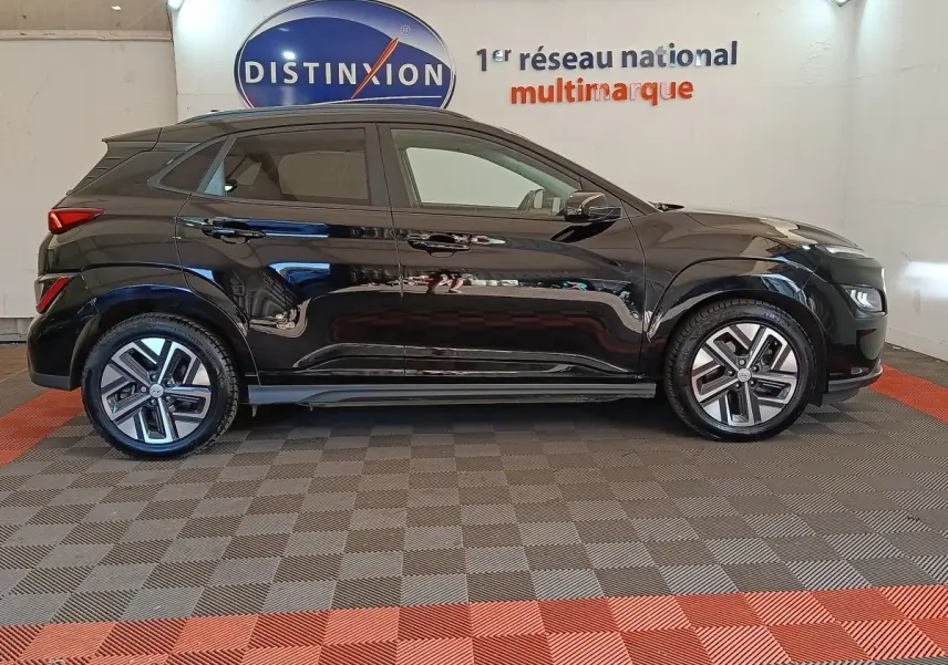 Vue de profil côté gauche d'un Hyundai Kona électrique noir 2023, avec jantes modernes et toit noir mat.