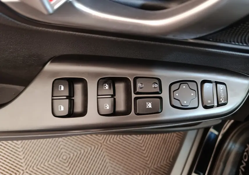 Vue rapprochée des commandes de porte côté conducteur du Hyundai Kona noir électrique 2023, avec boutons de vitres et rétroviseurs.