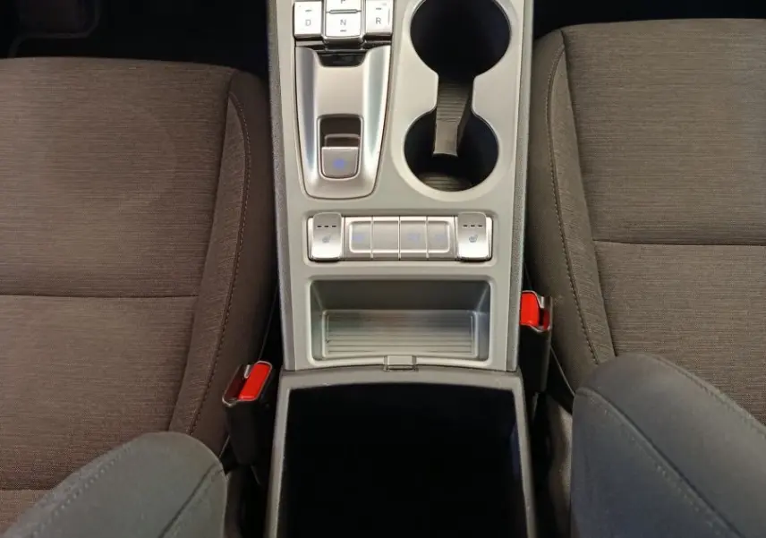 Vue plongeante sur la console centrale grise du Hyundai Kona électrique 2023, avec commandes de boîte auto et porte-gobelets.