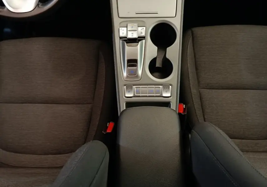 Vue intérieure plongeante sur la console centrale grise et les sièges tissu noirs du Hyundai Kona électrique 2023.