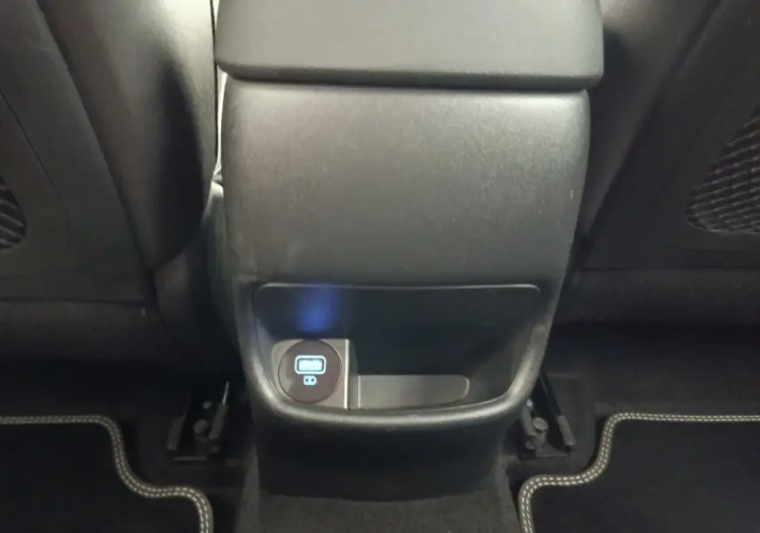 Prise USB arrière et rangement sous la console centrale du Hyundai Kona électrique noir, vue intérieure arrière.