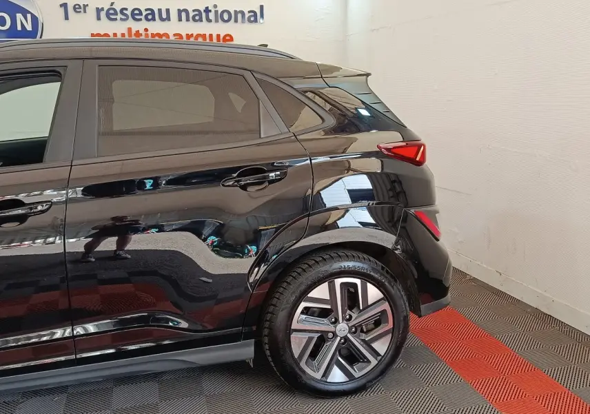Vue latérale arrière droite d'un Hyundai Kona électrique noir, mettant en valeur la roue et les feux arrière LED.