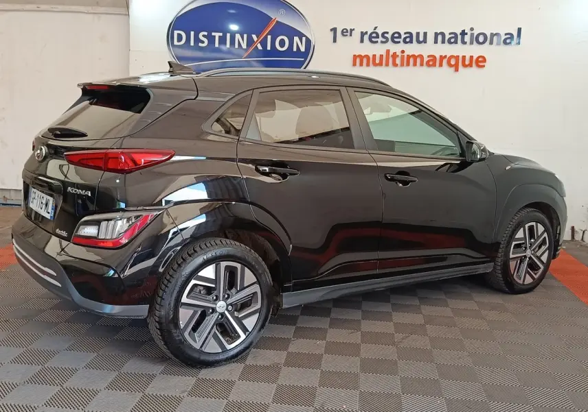 Hyundai Kona électrique noir vu de profil droit en intérieur avec jantes spécifiques et feux arrière LED.