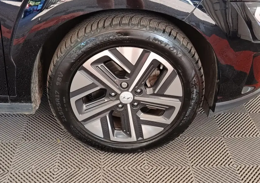 Gros plan sur la roue avant gauche noire d’un Hyundai Kona électrique 2023 avec jante alliage bicolore.