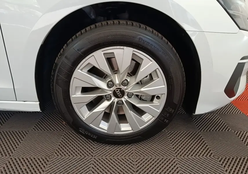 Gros plan sur la roue avant droite d’une Audi A3 blanche, mettant en valeur la jante en alliage et le pneu.