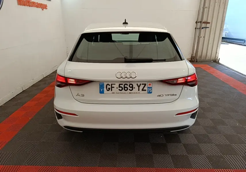 Vue arrière d'une Audi A3 blanche 40 TFSI e 2022 avec feux LED allumés dans un garage fermé.