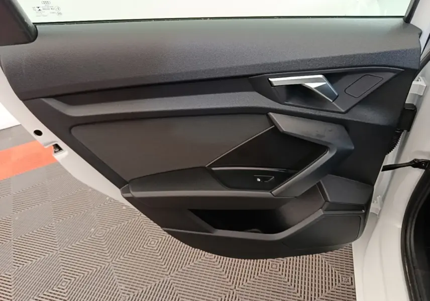 Vue intérieure côté gauche de la porte avant blanche d’une Audi A3 40 TFSI e avec garniture noire et poignée argentée.